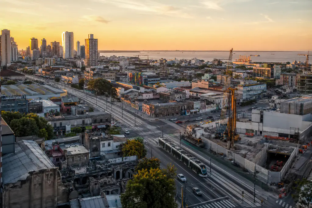 Vista aérea del sur porteño al atardecer, con un tranvía circulando y obras en construcción